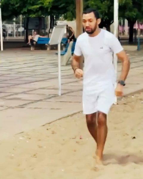 O aluno correndo descalço na areia.